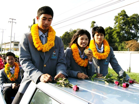 Noppakao Poonpat, flanked by fellow student teammates from the 2010 Asian Games, shows off her sailing gold medal in an open topped parade around Sattahip, Monday, November 29.